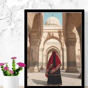 May include: Framed print of a person in traditional attire standing in a courtyard with arched columns and a domed structure. The person is wearing a red head covering and a black dress. The image is in a black frame.