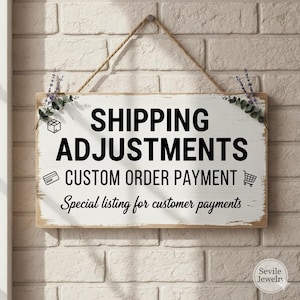 Op de afbeelding: Een rechthoekig houten bord met de woorden "SHIPPING ADJUSTMENTS CUSTOM ORDER PAYMENT" in het zwart. Het bord hangt aan een bakstenen muur met een touw en is versierd met groen.