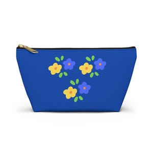 May include: A royal blue zippered pouch featuring a repeating pattern of small, stylized flowers in yellow and periwinkle blue. Each flower has a tiny orange center and is surrounded by small, rounded green leaves, creating a simple floral design.