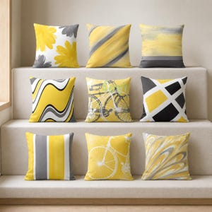 Peut inclure: Un ensemble de neuf coussins carrés présentant divers motifs jaunes, gris, noirs et blancs. Les designs incluent des motifs floraux, des rayures diagonales, des lavis aquarelle abstraits, des lignes ondulées, un vélo et des grilles géométriques.