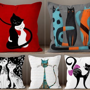 Può includere: Set di cinque cuscini decorativi con disegni di gatti. I cuscini presentano varie illustrazioni di gatti in nero, bianco, blu, arancione e motivi su sfondi rossi, grigi e bianchi. Ideale per gli amanti dei gatti.