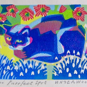 Puede incluir: Un gato azul y blanco con ojos verdes está tumbado en un campo de flores blancas. El gato está rodeado de flores rosas y rojas. La imagen es una impresión en madera titulada "Purrfect Spot" de Underwood.