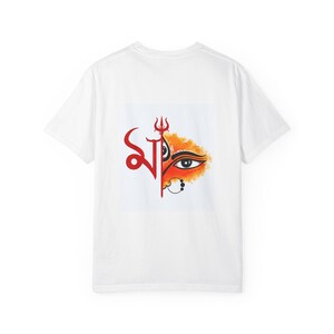 Op de afbeelding: Een wit T-shirt met korte mouwen en een grafische print in het midden. Het ontwerp toont een rood Bengaals schriftteken aan de linkerkant, een rood drietandsymbool erboven en een gestileerd oog met oranje aquarelachtige schaduw aan de rechterkant.