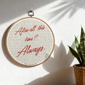 Peut inclure: Un cercle de broderie en bois avec la citation "After all this time? Always." en rouge. Le fond est une page imprimée d'un livre. Un objet décoratif pour un fan d'Harry Potter.