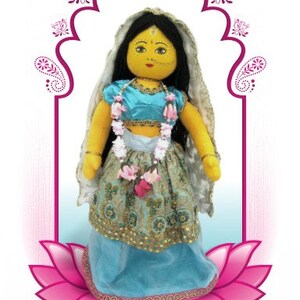 May include: A handmade doll dressed in a turquoise and gold embroidered outfit, adorned with a floral garland and a veil. The doll has black hair, a yellow face, and is set against a pink lotus flower and an archway design.