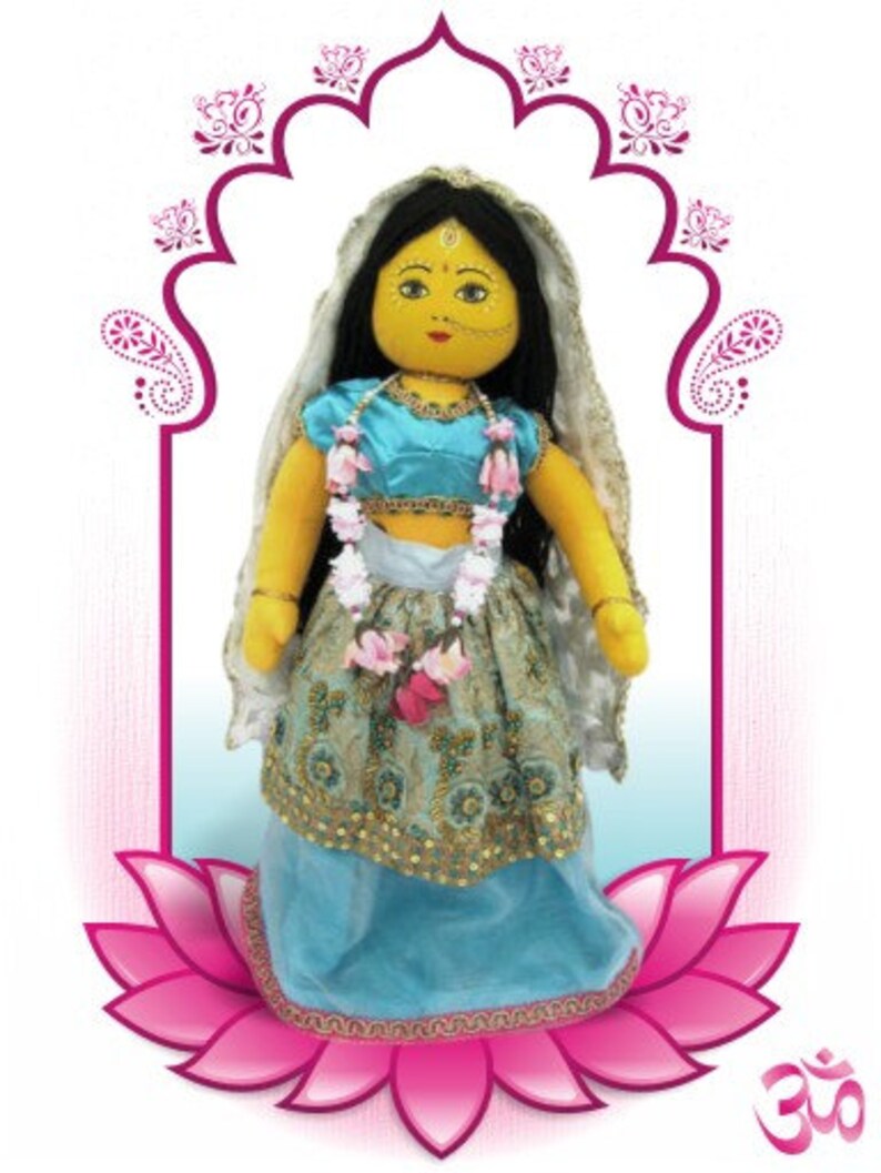 May include: A handmade doll dressed in a turquoise and gold embroidered outfit, adorned with a floral garland and a veil. The doll has black hair, a yellow face, and is set against a pink lotus flower and an archway design.