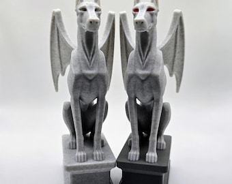 Può includere: Due statue di gargoyle a forma di cane grigio con ali di pipistrello, sedute su piedistalli. Uno ha gli occhi rossi. Le statue hanno superfici strutturate e sono su sfondo bianco. Il testo "TinkerLayer" è in basso.