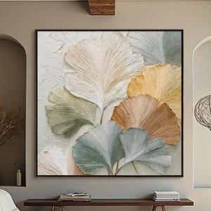 Peut inclure: Une grande œuvre d'art encadrée présente un motif abstrait texturé de feuilles stylisées dans des tons de blanc, vert, jaune et marron. L'œuvre est suspendue au-dessus d'un banc en bois et d'un canapé crème dans un salon moderne.