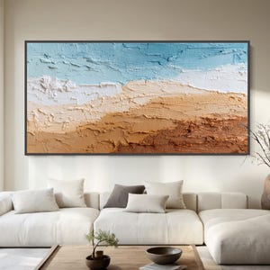 May include: Abstract landscape painting with a textured surface, showing layers of colour. The artwork features a gradient from light blue at the top to white, tan, and brown at the bottom, framed in black. The painting is a large size.