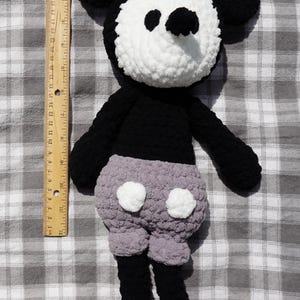 May include: A handmade crochet Mickey Mouse doll. The doll features a white face, black ears, arms, and legs, and gray shorts with white buttons. The doll is approximately 18 inches tall.