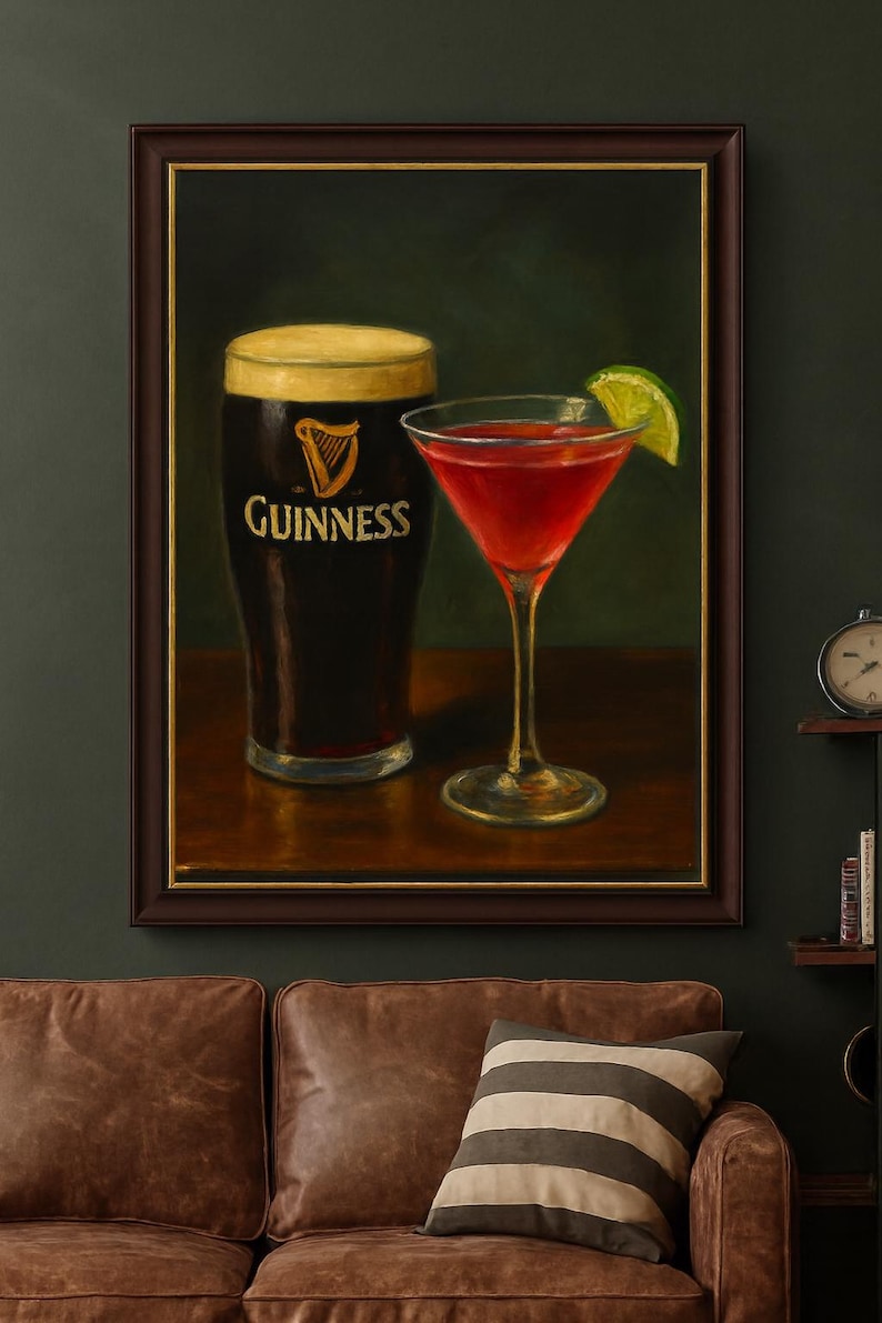 K&ouml;nnte beinhalten: Gerahmtes Gem&auml;lde mit einem Pint Guinness und einem roten Cocktail mit Limettenscheibe. Das Guinness-Glas zeigt den Markennamen und das Harfenlogo. Das Bild hat einen dunkelgr&uuml;nen Hintergrund.