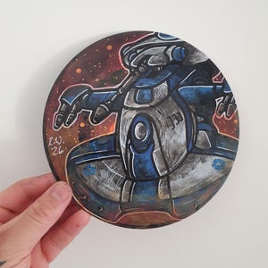 May include: Circular artwork depicting a futuristic robot in blue, grey, and silver tones. The robot is set against a dark brown and orange background with a starry effect. Signed "R.W. '26" in the lower left corner.
