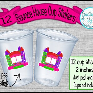 May include: Two clear plastic cups with stickers featuring a colorful bounce house design. The stickers are 2 inches and read "12 Bounce House Cup Stickers". The text "Just peel and stick" is also visible.