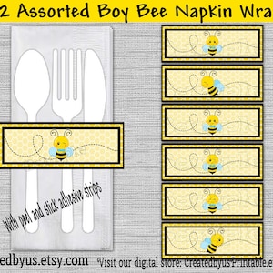 May include: Twelve printable bee-themed napkin wraps with a yellow and black honeycomb pattern. Each wrap features a cartoon bee with a blue and yellow striped body and a winking face. The text "With peel and stick adhesive strips" is printed on the wrap.