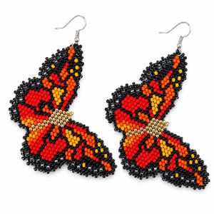 Op de afbeelding: Een paar kralen oorbellen in de vorm van een vlinder. De oorbellen hebben een gedetailleerd ontwerp met rode, oranje, gele en zwarte kralen. De vleugels hebben een zwarte rand en een goudkleurig midden.