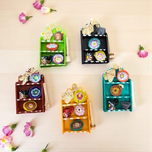 Può includere: Una collezione di mensole decorative in miniatura, colorate, ognuna con un design unico. Le mensole sono dipinte in vari colori, tra cui verde, nero, marrone, giallo e turchese. Ogni mensola contiene piatti e tazze in miniatura.