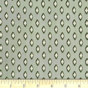 May include: A fabric with a repeating pattern of green diamond shapes, each containing a white floral design. The background is a muted green color. A ruler is at the bottom of the image, showing measurements in inches.