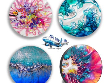 Könnte beinhalten: Vier runde Untersetzer mit abstrakten Kunstdesigns. Die Untersetzer zeigen leuchtende Farben wie Rosa, Blau, Grün und Gelb. Ein Untersetzer hat den Text "Pilot Wife Life Live Life Simple" mit einer Flugzeuggrafik.