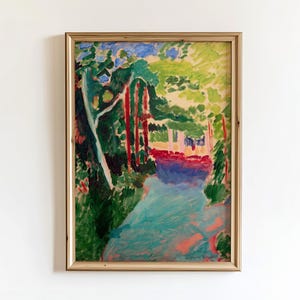 May include: A framed landscape painting in a gold-coloured frame. The artwork shows a colourful forest scene with a blue river, red trees, and green foliage. The painting has a vibrant, impressionistic style.