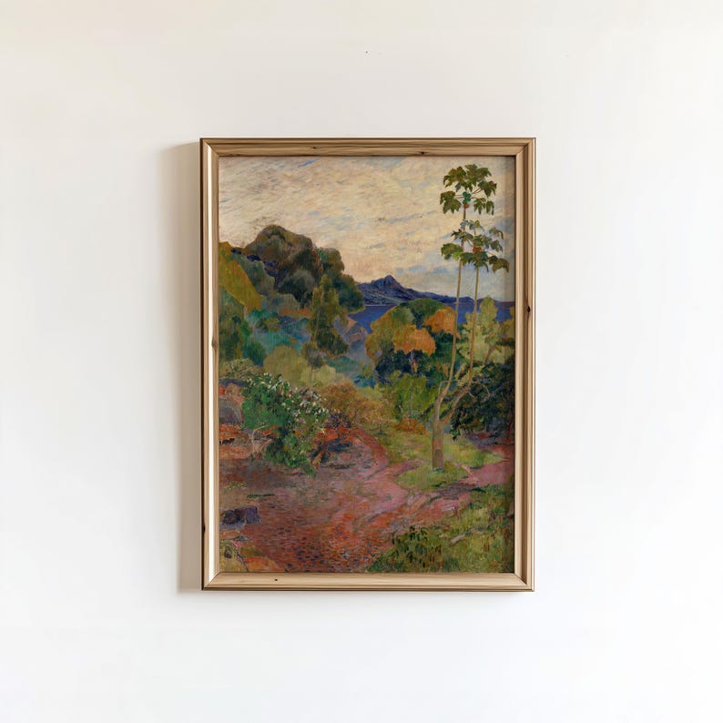 May include: A framed landscape painting with a warm color palette. The artwork depicts a lush, green hillside with trees and a path leading towards a body of water. The sky is a mix of blue and white, and the frame is a light brown.