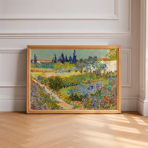 May include: A framed landscape painting with a wooden frame. The artwork depicts a colorful garden scene with a path, flowers, trees, and a wall. The painting's colors include blues, greens, yellows, and reds.