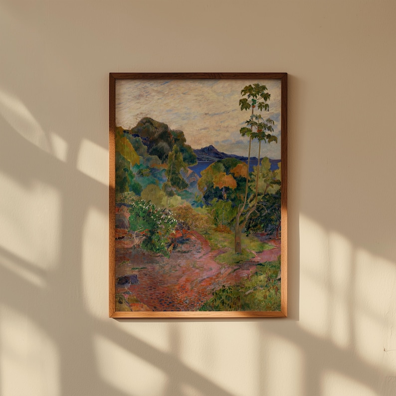 May include: A framed landscape painting with a vibrant color palette. The artwork depicts a lush, green forest with a winding path, a body of water, and a cloudy sky. The frame is a warm, natural wood tone.
