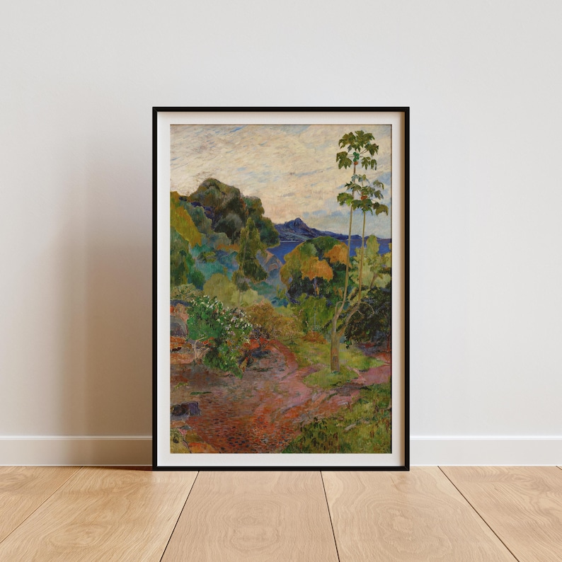 May include: A framed landscape print featuring a vibrant scene of lush green trees, a winding red path, and a body of water under a cloudy sky. The artwork is displayed in a black frame, adding a touch of elegance to the naturalistic scene.