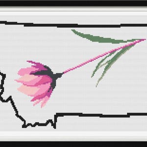 May include: Cross-stitch art print featuring the outline of Montana in black, filled with a white background. A pink and green flower design is centered within the state's borders. The artwork is framed in a black frame with a white mat.