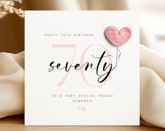 May include: A white birthday card with the text "Happy 70th Birthday" and "seventy" in a script font. A pink crocheted heart is attached to the card. The card also includes the text "To a very special friend Deborah".