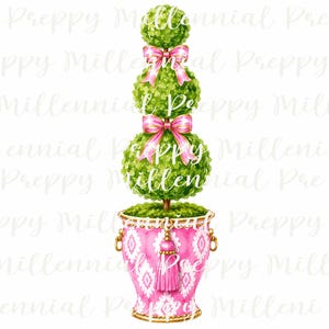Può includere: Un topiario con tre sezioni di fogliame verde sferiche impilate, ciascuna decorata con un fiocco di nastro rosa. La pianta è posta in un'urna rosa con un motivo geometrico bianco, manici laterali dorati e una nappa decorativa rosa centrale.