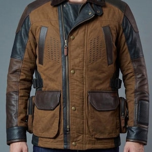 May include: A brown and black jacket with multiple pockets, a fur collar, and leather accents. The jacket has a zipper and button closure, with dark patches on the shoulders and sleeves. The jacket has a rugged, outdoorsy aesthetic.