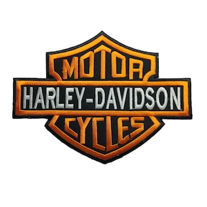 Può includere: Una toppa ricamata con il logo Harley-Davidson Motor Cycles. Il design presenta un contorno a scudo nero con bordi arancioni, la parola MOTOR in arancione, il testo HARLEY-DAVIDSON in bianco e la parola CYCLES in arancione.