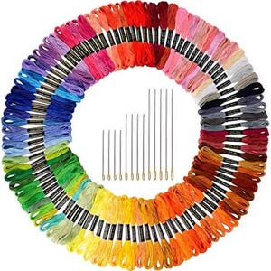 Puede incluir: Una disposición circular de hilos de bordar coloridos en un arcoíris de tonos, incluyendo rojo, naranja, amarillo, verde, azul y morado. Un juego de agujas de bordar está en el centro. Este conjunto de suministros de manualidades es ideal para bordar y punto de cruz.