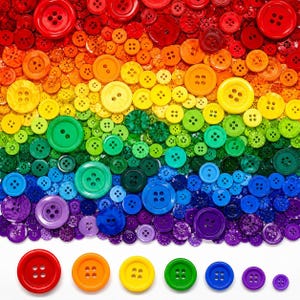 May include: A collection of round plastic buttons arranged in a rainbow gradient pattern, featuring various sizes and shades of red, orange, yellow, green, blue, and purple, with six individual buttons displayed in a row at the bottom.