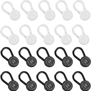 May include: A collection of twenty elastic button extenders arranged in four rows. The top two rows feature ten white circular buttons with a crown and wreath emblem. The bottom two rows feature ten black circular buttons with the same emblem.