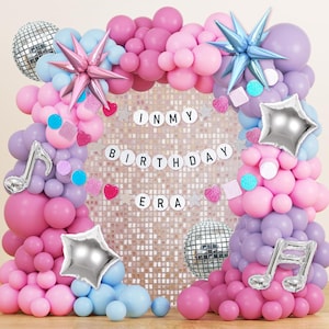 Puede incluir: Un vibrante conjunto de decoración de fiesta de cumpleaños con un arco de globos en tonos rosa, morado y azul. Incluye globos de estrella, bolas de discoteca y una pancarta que dice "IN MY BIRTHDAY ERA".