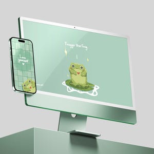 Puede incluir: Un monitor de computadora y un teléfono inteligente de color verde menta muestran un diseño de rana de dibujos animados. El monitor muestra "Froggo the Frog" y una rana con un corazón. El teléfono muestra "Love yourself" y una rana.