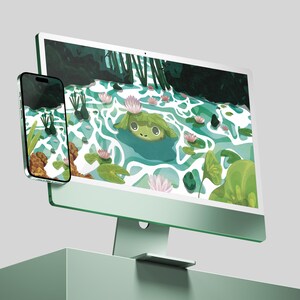 Op de afbeelding: Een mintgroene desktopcomputer en smartphone tonen een grillige illustratie van een kikker in een vijver met waterlelies en roze bloemen. De apparaten staan op een bijpassend mintgroen oppervlak.