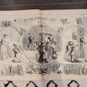 May include: An open book featuring a black and white illustration titled "St. Valentine's Day 1864." The image depicts various scenes with figures, including cherubs, families, and individuals in period clothing, creating a historical and romantic theme.