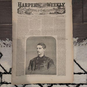 Peut inclure: Un exemplaire vintage de Harper's Weekly, un journal de civilisation, datant de mars 1864. Le journal présente un portrait d'un homme en uniforme militaire. Le papier est vieilli et usé.