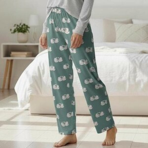 Puede incluir: Pantalones de pijama color verde azulado con un estampado de cisnes blancos. Los pantalones tienen cintura con cord&oacute;n y un ajuste relajado. Los cisnes est&aacute;n dispuestos en parejas, creando un dise&ntilde;o repetitivo. Los pantalones son de tela suave y ligera.