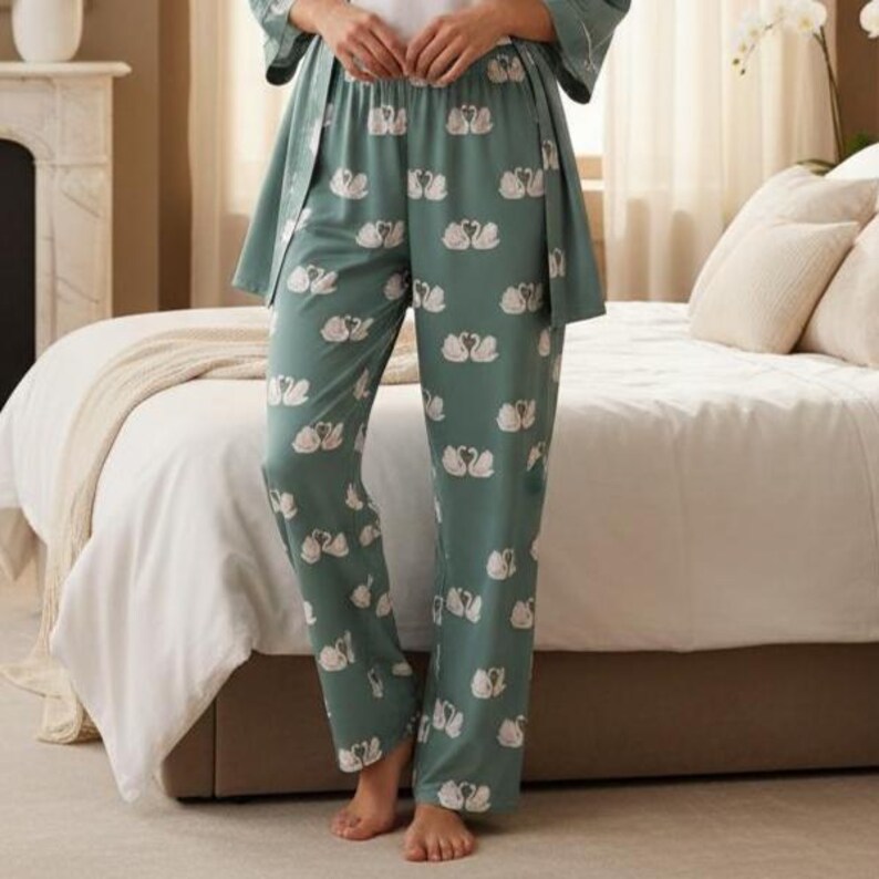 Puede incluir: Pantalones de pijama verdes con un estampado de cisnes blancos. Los pantalones forman parte de un conjunto a juego y est&aacute;n hechos de una tela suave y fluida. Los cisnes est&aacute;n dispuestos en un patr&oacute;n repetido.