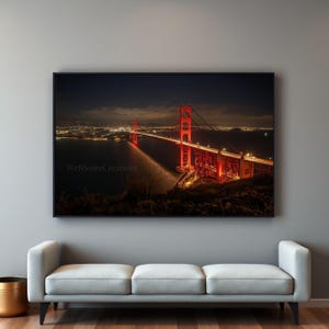 May include: A framed print of the Golden Gate Bridge at night. The iconic red bridge is illuminated, with city lights in the background. The image has a long exposure, creating light trails. The text "WebStoreCreativity" is visible.