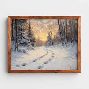 Op de afbeelding: Een ingelijst winterlandschapsschilderij. Het kunstwerk toont een met sneeuw bedekt pad dat door een bos slingert, met voetstappen in de sneeuw. De lucht is warm oranje en geel, wat duidt op een zonsopgang of zonsondergang. De lijst is van hout.