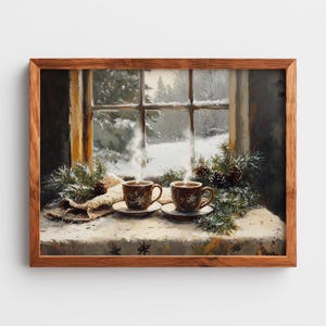 Puede incluir: Pintura enmarcada que representa una escena invernal. Dos tazas de café humeantes sobre platillos se encuentran sobre una mesa cerca de una ventana con vistas a un paisaje nevado. Ramas de pino y piñas completan el tema invernal.