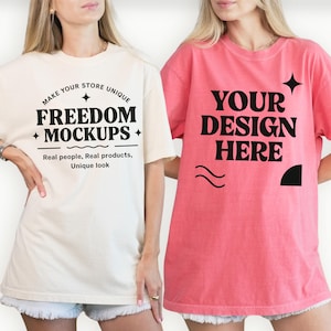 May include: Two oversized t-shirts. One is cream-colored with the text "MAKE YOUR STORE UNIQUE FREEDOM MOCKUPS Real people, Real products, Unique look." The other is pink with the text "YOUR DESIGN HERE" and decorative elements. Both shirts have short sleeves.