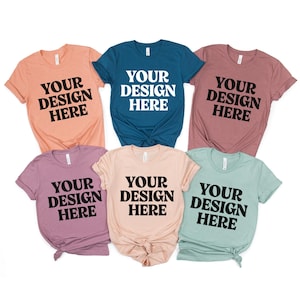 Könnte beinhalten: Sechs kurzärmelige T-Shirts in verschiedenen Farben, darunter Pfirsich, Türkis, Malve und Mintgrün. Jedes Shirt zeigt den Text "YOUR DESIGN HERE" in fetter, schwarzer Schrift, ideal für individuelle Designs.