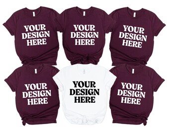 May include: Six t-shirts, in a variety of colors, are displayed. Five are a deep burgundy color, and one is white. Each shirt has the text "YOUR DESIGN HERE" printed in a bold, sans-serif font.