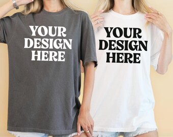 May include: Two short-sleeved t-shirts, one charcoal gray and one white, each with the text "YOUR DESIGN HERE" in bold, white capital letters. The shirts are being modeled.