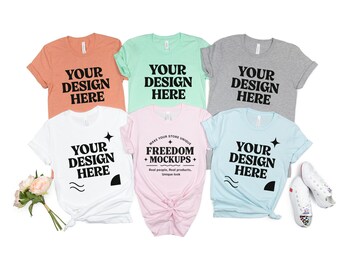 May include: A collection of six t-shirts in various colors, including peach, mint green, gray, white, light pink, and light blue. Each shirt features the text "YOUR DESIGN HERE" in bold black font. The pink shirt also has the text "FREEDOM + MOCKUPS".